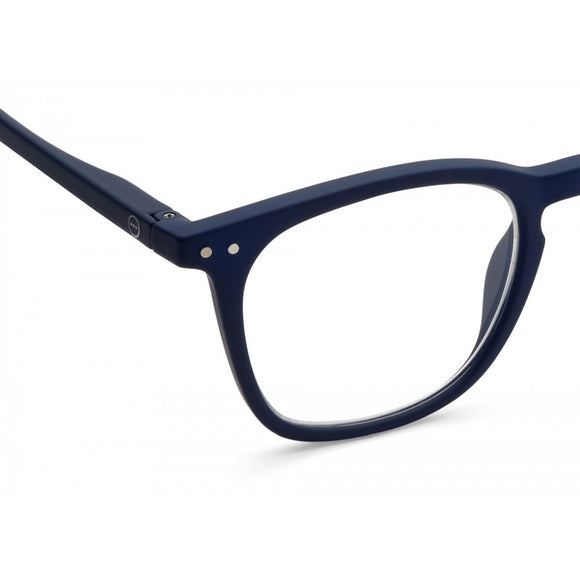 A navy blue  pair of magnifying reading glasses. The frames are a large, structured, trapezium shape. 