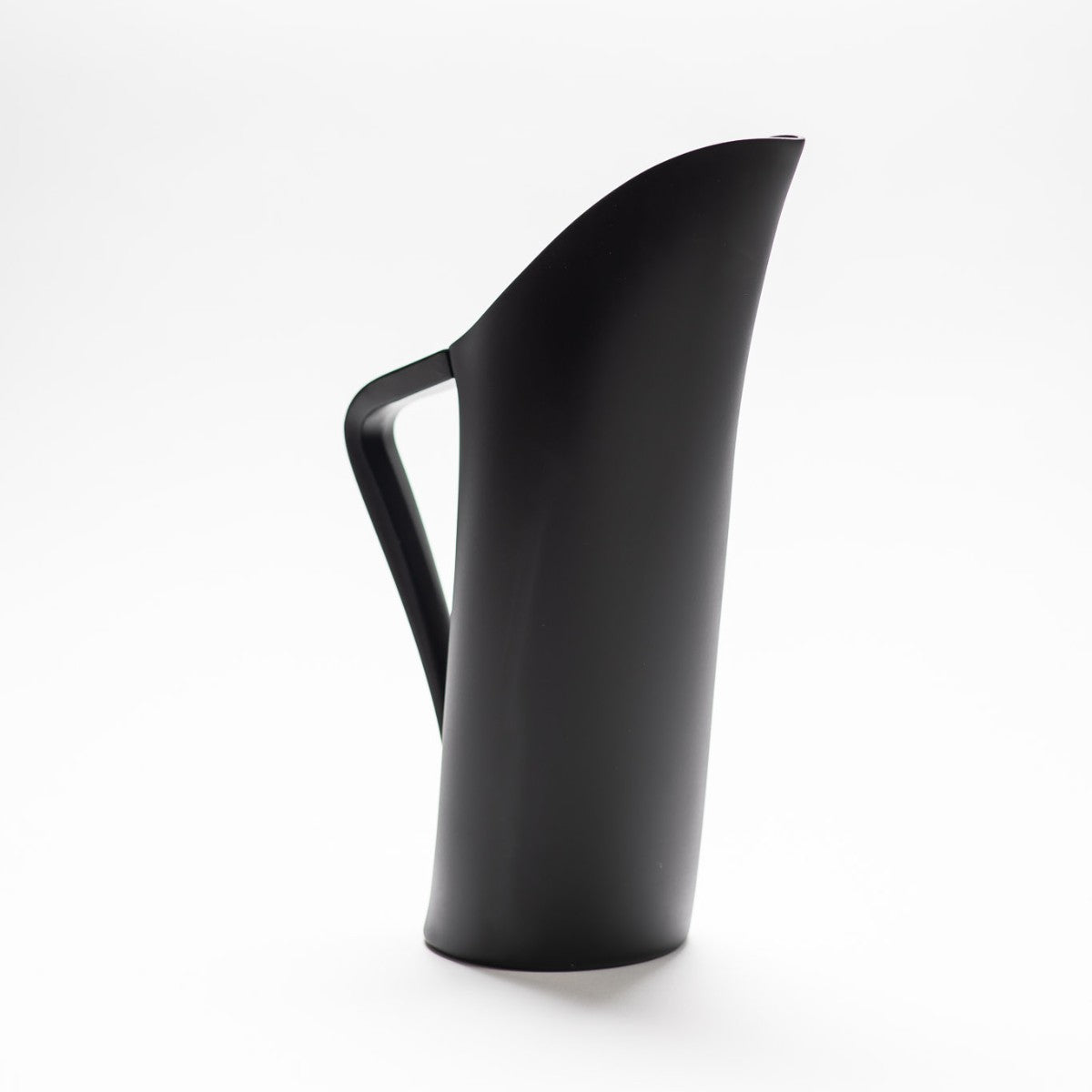 A black matte jug with arched spout seamlessly continuing down to its handle.