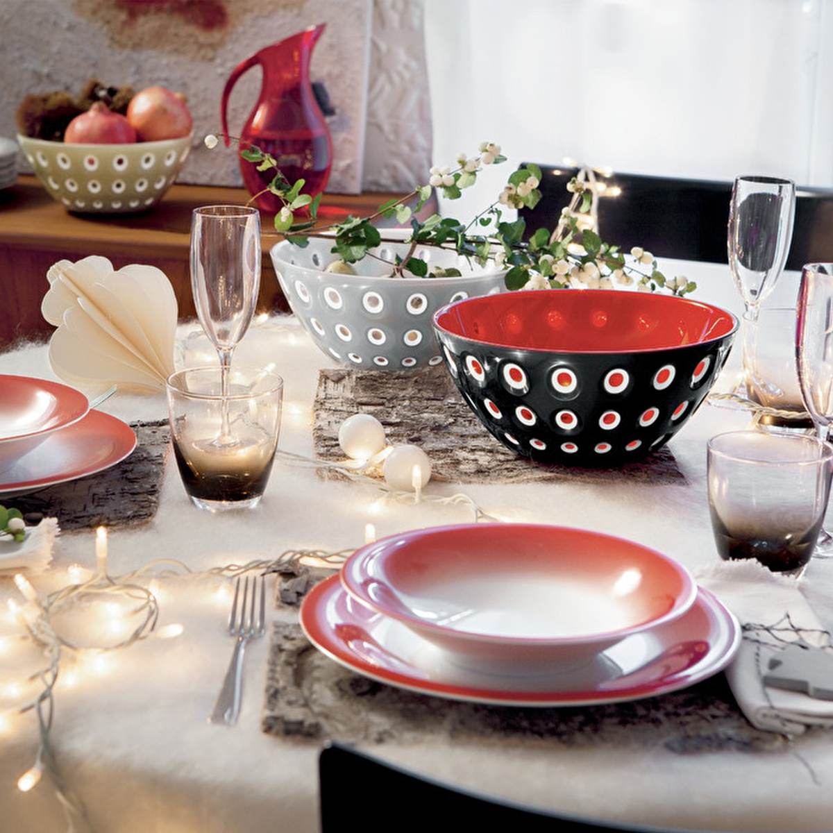 A table decorated and set with dinner plates in shades of red, black and white that tie in with the black & red Guzzini bowl in the centre.