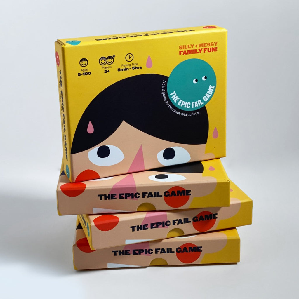 A stack of yellow boxes has their sides showing "The epic fail game" in black. On the top is the cover of The Epic Fail Game box with a face looking up and "silly + messy Family Fun!" in red on the top right corner. 