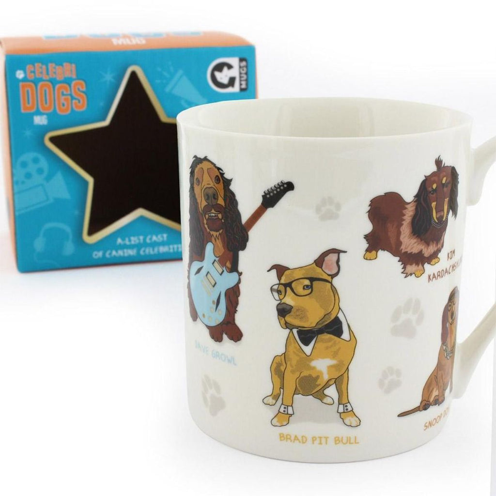 In front of an empty blue packaging box is a white Celebri Dog mug with dogs illustrated as their pun celebrity counterparts, such as a blonde staffy wearing glasses and a bowtie with 'Brad Pit Bull' below it. 