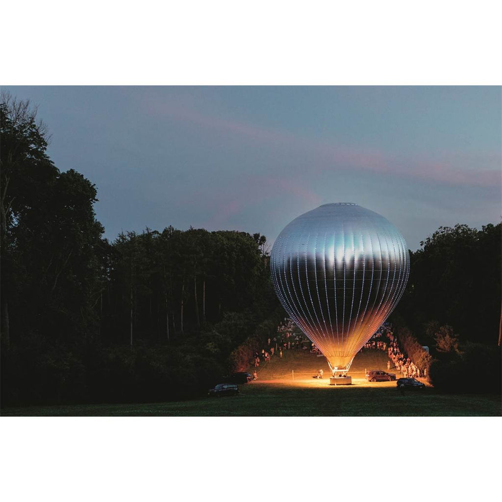 A double-page spread features a coloured photograph of a silver hot air balloon in a park at dusk. 