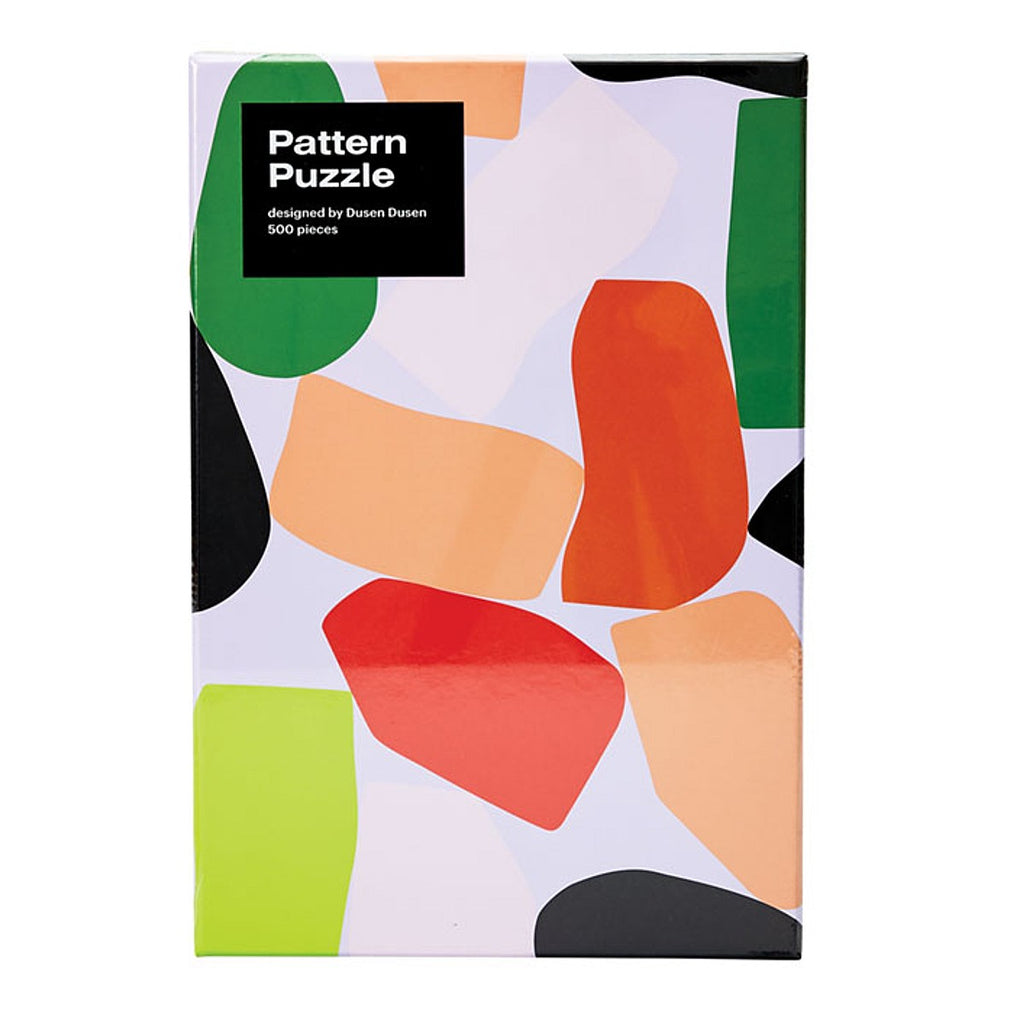 A 500 piece puzzle featuring an abstract design by Dusen Dusen. Geometric and abstract shapes in red, orange, cream, light green and dark green on a pastel purple base.