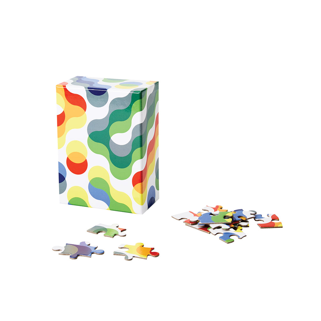 The rectangular white packaging box with a colourful squiggly amorphous pattern has its corresponding pieces scattered in front. 