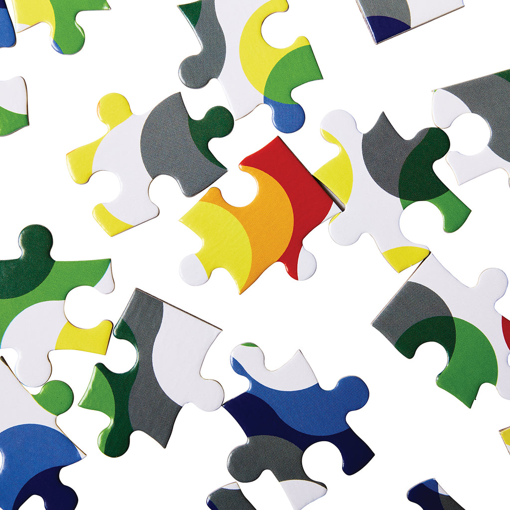 A close up of the puzzle pieces shows curved shapes of colours overlapping on a white background. 