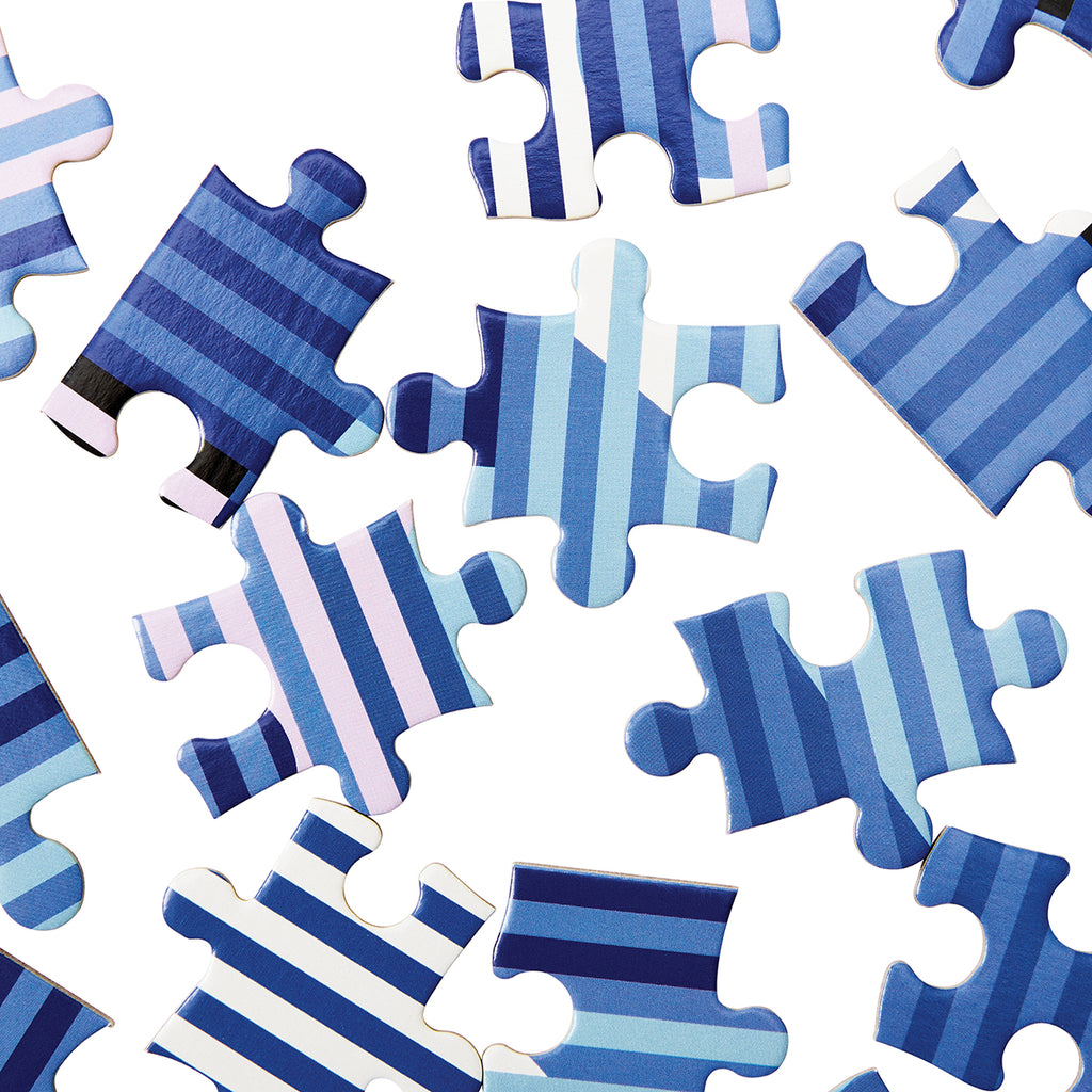 A close up of the puzzle pieces shows various blue shades stricken by the horizontal stripes in different tones. 