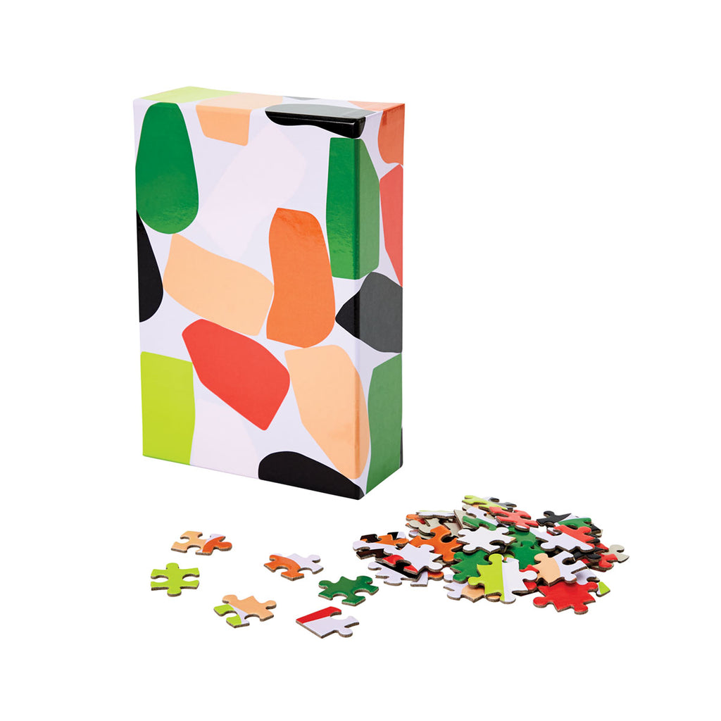 The rectangular lavender packaging box with colourful odd-shaped blocks has its corresponding pieces scattered in front. 