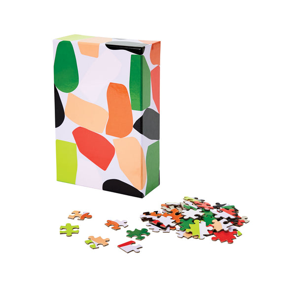 A completed puzzle has a pattern of odd-shaped blocks in green, orange, black, white and red precariously balanced over a pastel purple background. 