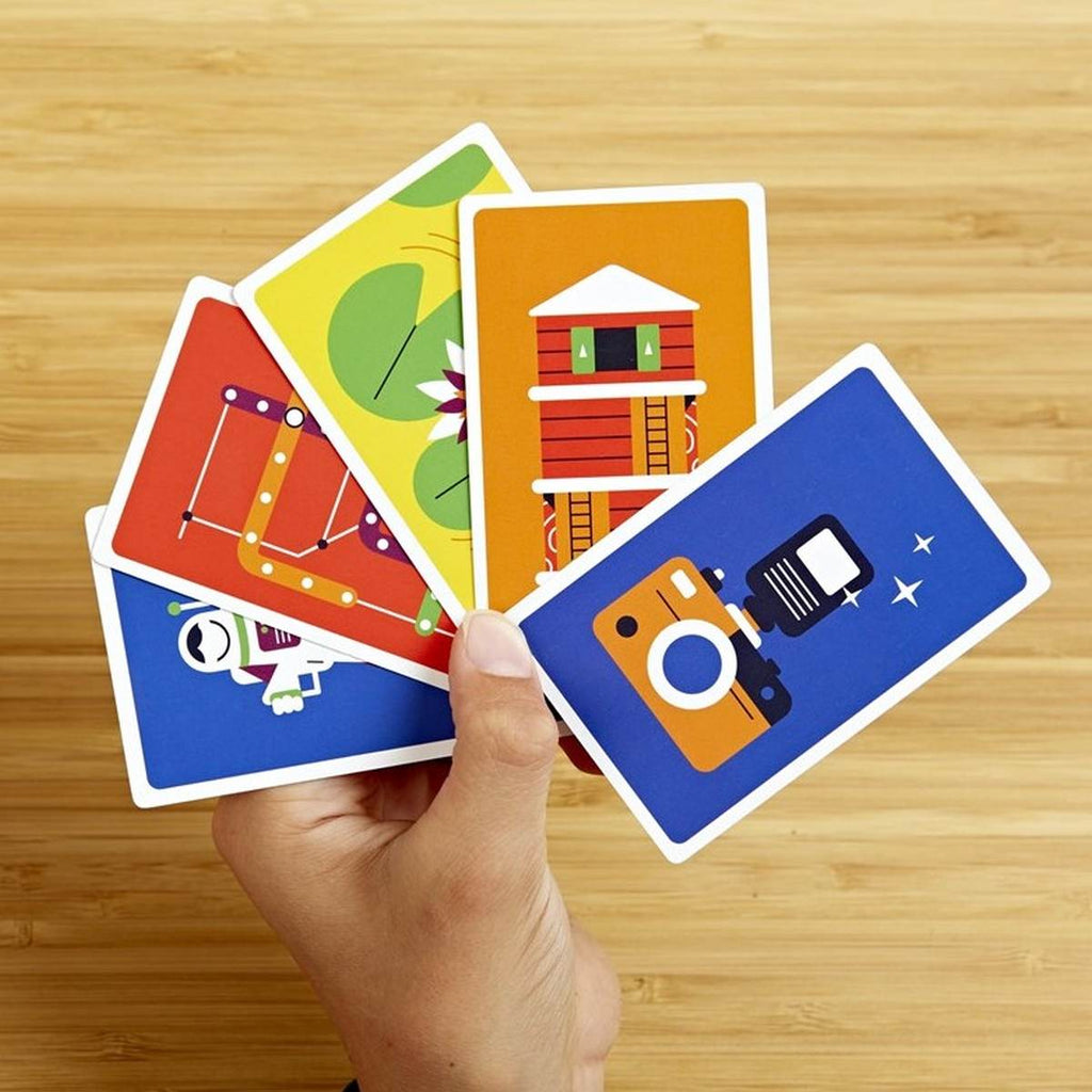 A hand fanned out cards with varied simplistic graphics such as a camera with flash on different coloured backgrounds. 