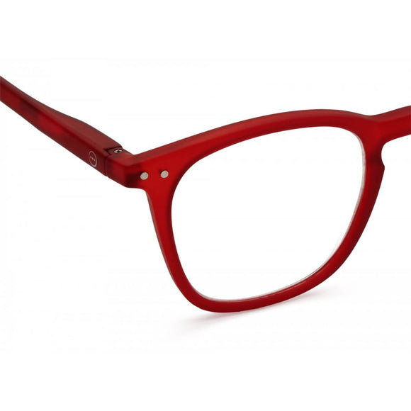 A pair of slightly translucent red magnifying reading glasses. The frames are a large, structured, trapezium shape.