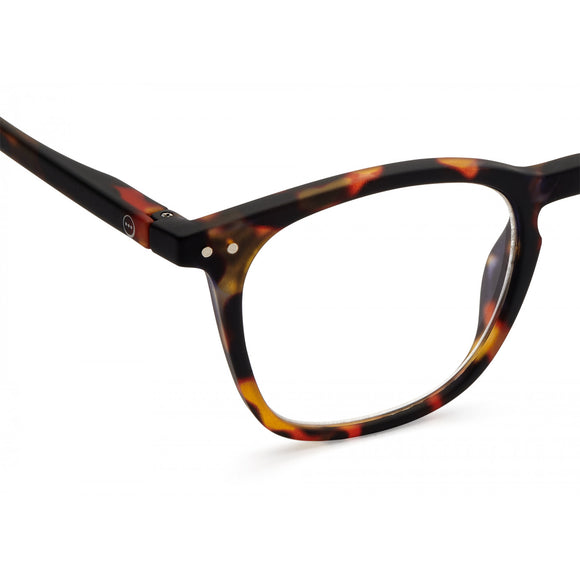 A pair of magnifying reading glasses. The frames are a large, structured, trapezium shape in a mottled classic tortoise shell finish.