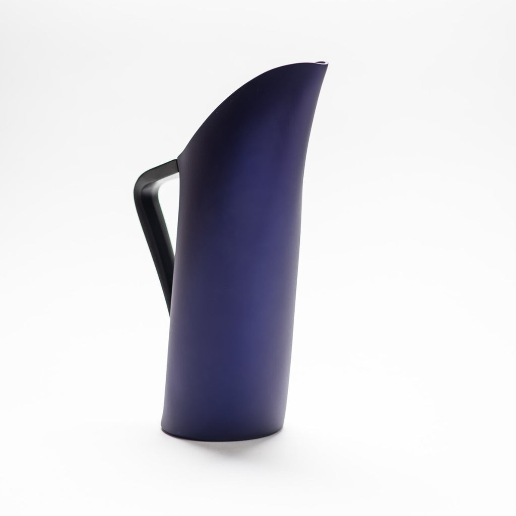 A indigo blue matte jug with arched spout seamlessly continuing down to its handle. 