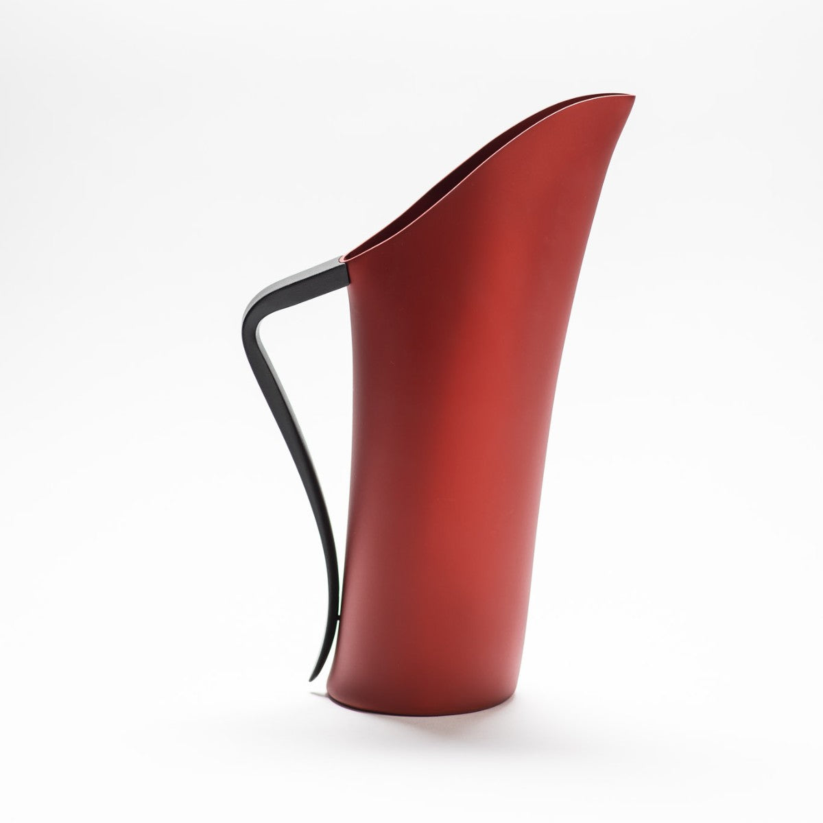 A finely designed sculptural deep red jug made of anodised aluminium.