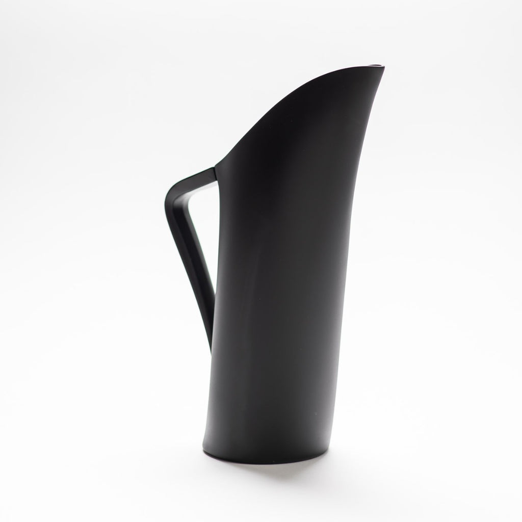 A black matte jug with arched spout seamlessly continuing down to its handle. 