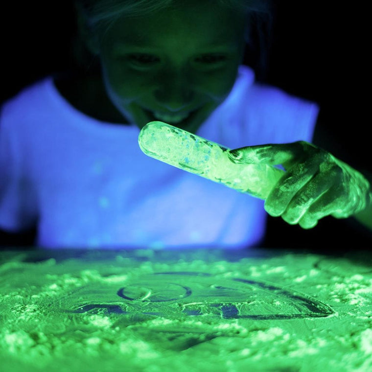 Photograph of a young child playing with a phosphorescent powder in a test tube