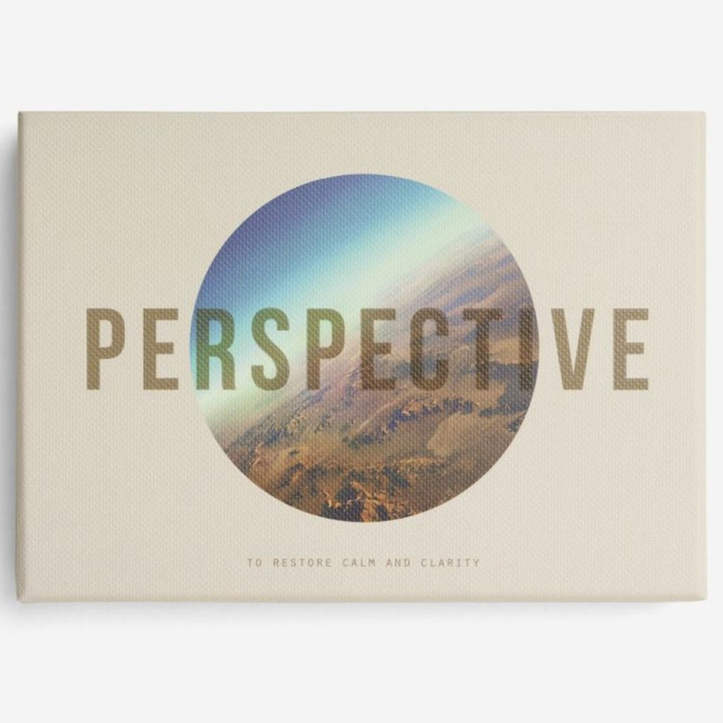 A cream rectangular packaging box has 'perspective' capitalised in a translucent caramel font over a circle with a photograph of the sky over a desert plain in the middle. 