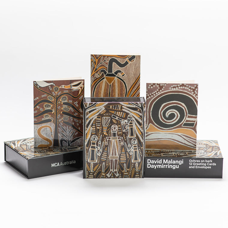 In a stacked pyramid formation are the Greeting Card Boxed Sets showcasing a few different greeting card covers with David Malangi Daymirringu's ochres on bark artworks. 