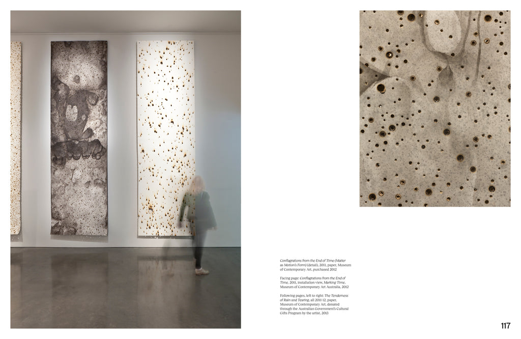 Photograph of "Conflagrations From The End of Time" installation view on the left page displaying two vertical panels draping from the wall. A detailed image of the same artwork on the right page highlighting the burnt holes on the grey stained paper. 