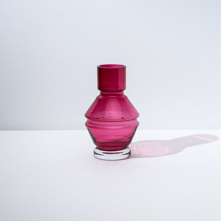 A structural and ridged glass vase in a deep pink red tone