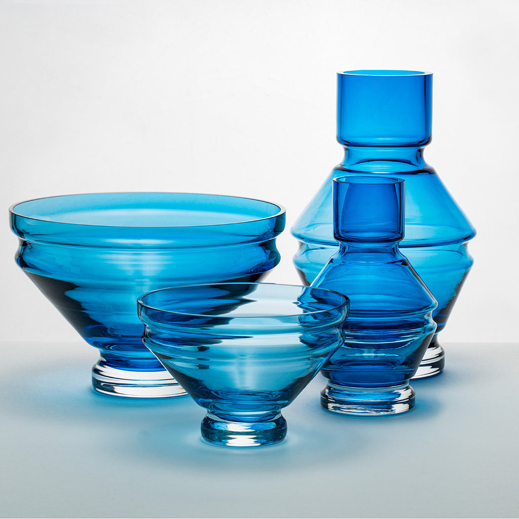 A collection of blue glass vases and bowls, showcasing the refractions that the grooves create.