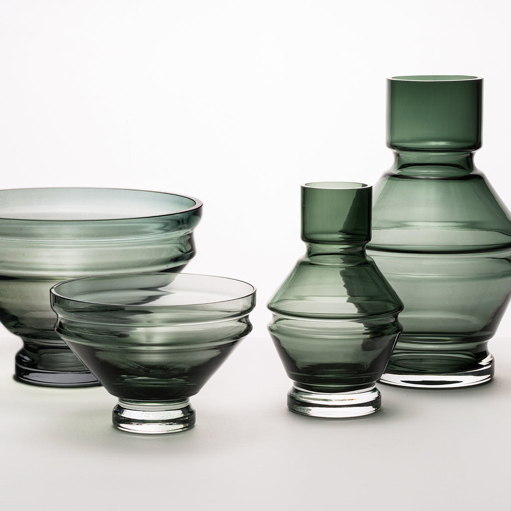A collection of smokey grey glass vases and bowls, showcasing the refractions that the grooves create.