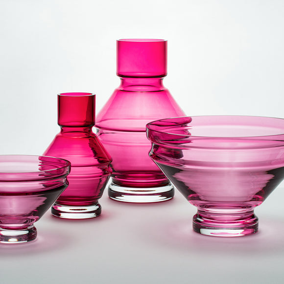 A structural and ridged glass vase in a deep pink red tone