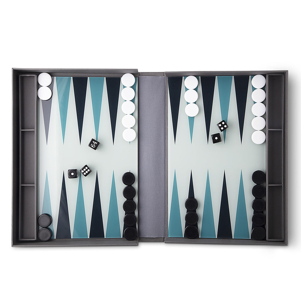 An open dark grey backgammon set reveals a pastel teal board with grey, teal and navy triangles, black and white dice, and playing pieces. 