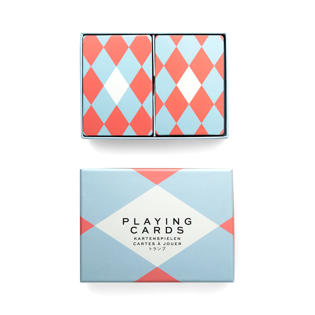 An opened rectangular box contains two deck of cards with a white diamond in the centre of the red and light blue diamond pattern. Below is the lid of the packaging box with a matching red and blue pattern, and at the centre white diamond is 'playing cards' in black. 