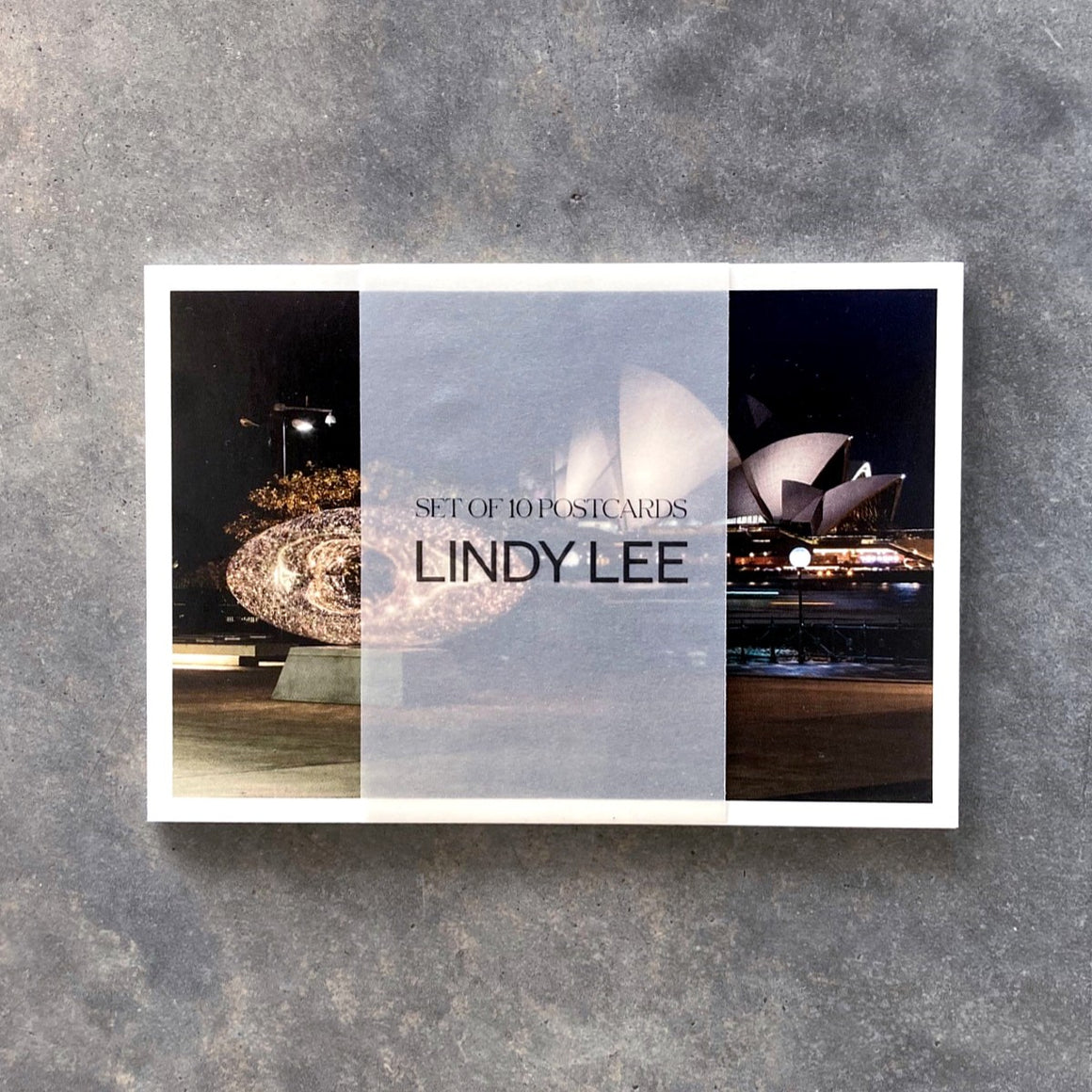 A pack of postcards featuring reproductions of Lindy Lee's artworks. The pack of 10 are held together by a semi translucent paper wrap