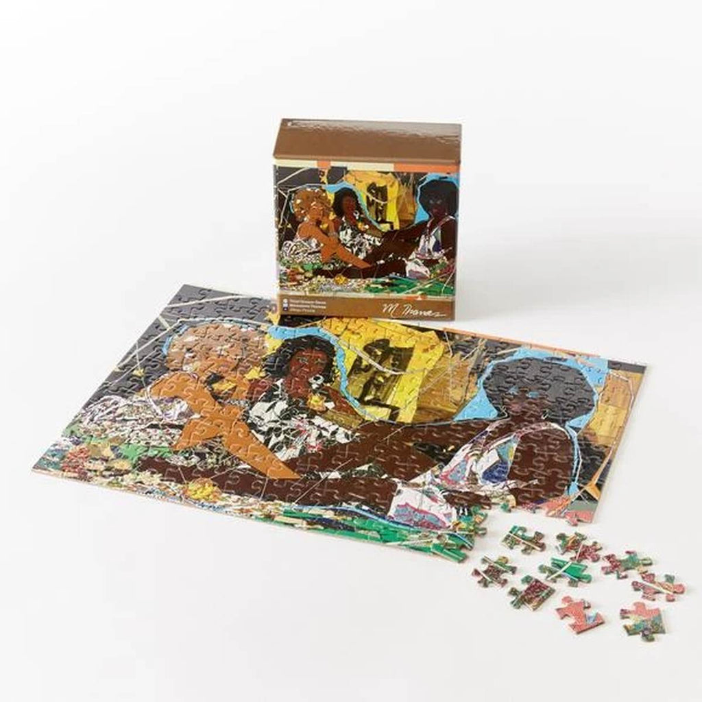 An almost completed puzzle of three brown women in patterned dresses is in front of its brown box. 