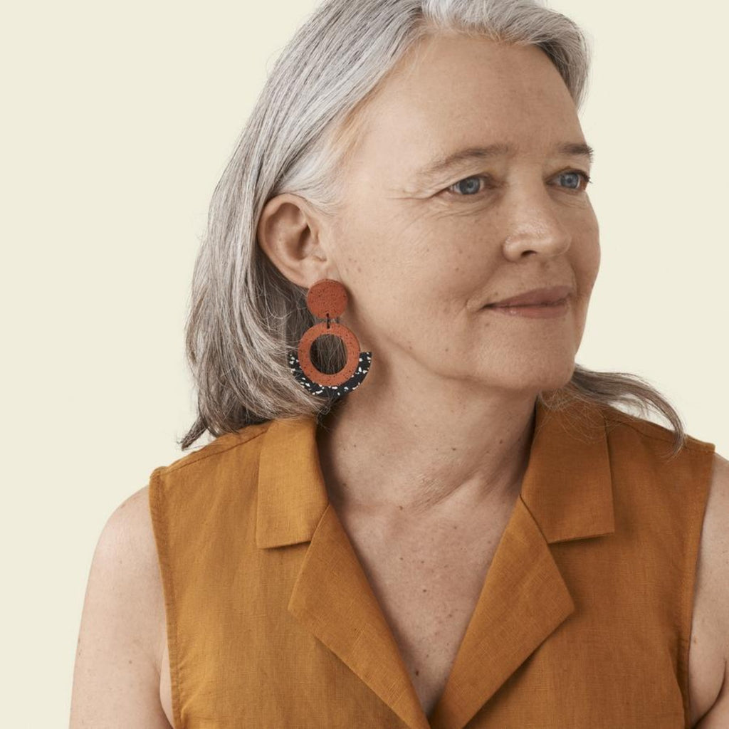 Photograph of a older woman wearing a pair of the sunrise penny hoop earrings on her left ear