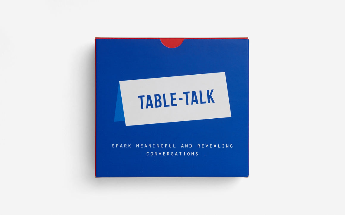 An ultramarine blue packaging box has a white rectangle, mimicking a table card, with "table-talk" capitalised in ultramarine blue font. At the bottom, in white and capitalised font is "spark meaningful and revealing conversations".  