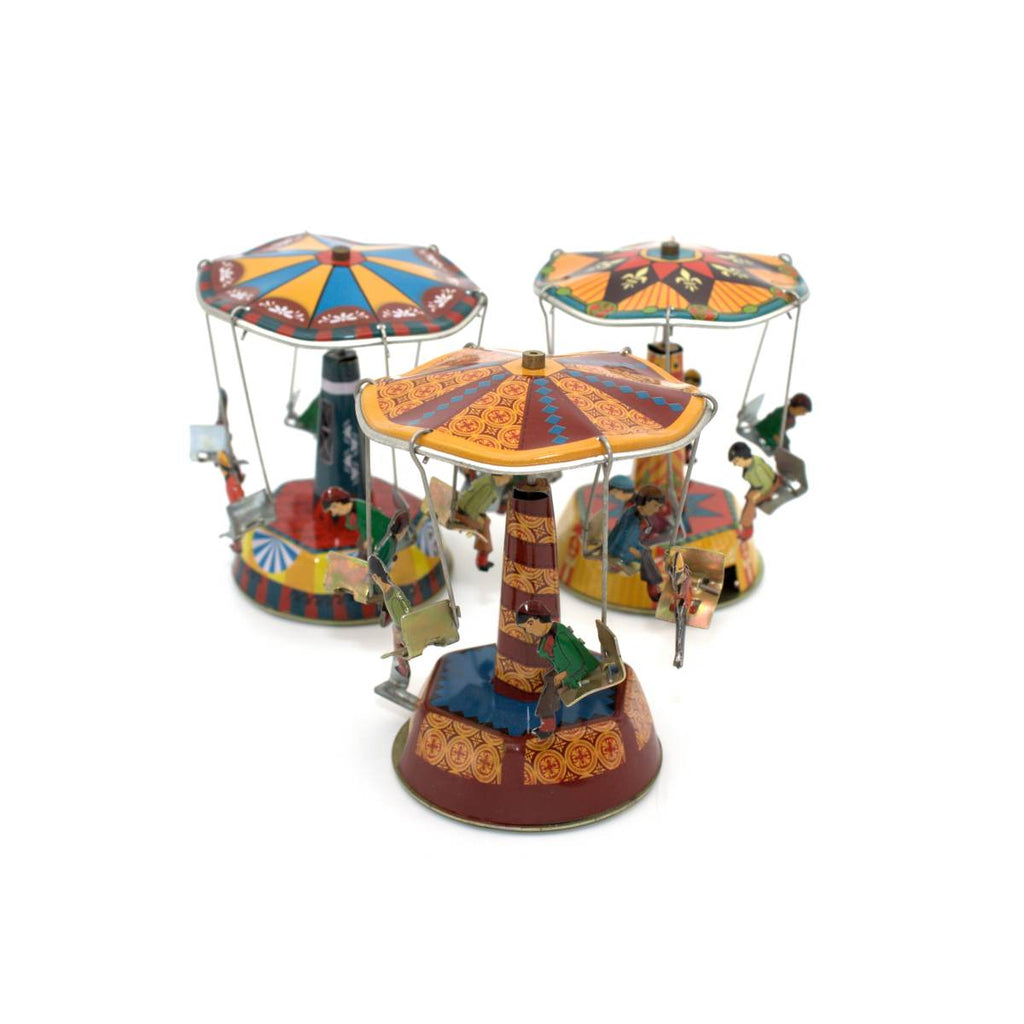 Three tin toy carousels in primary colours. Each carousel has 6 seats suspended from the canopy, with small figures seated on each