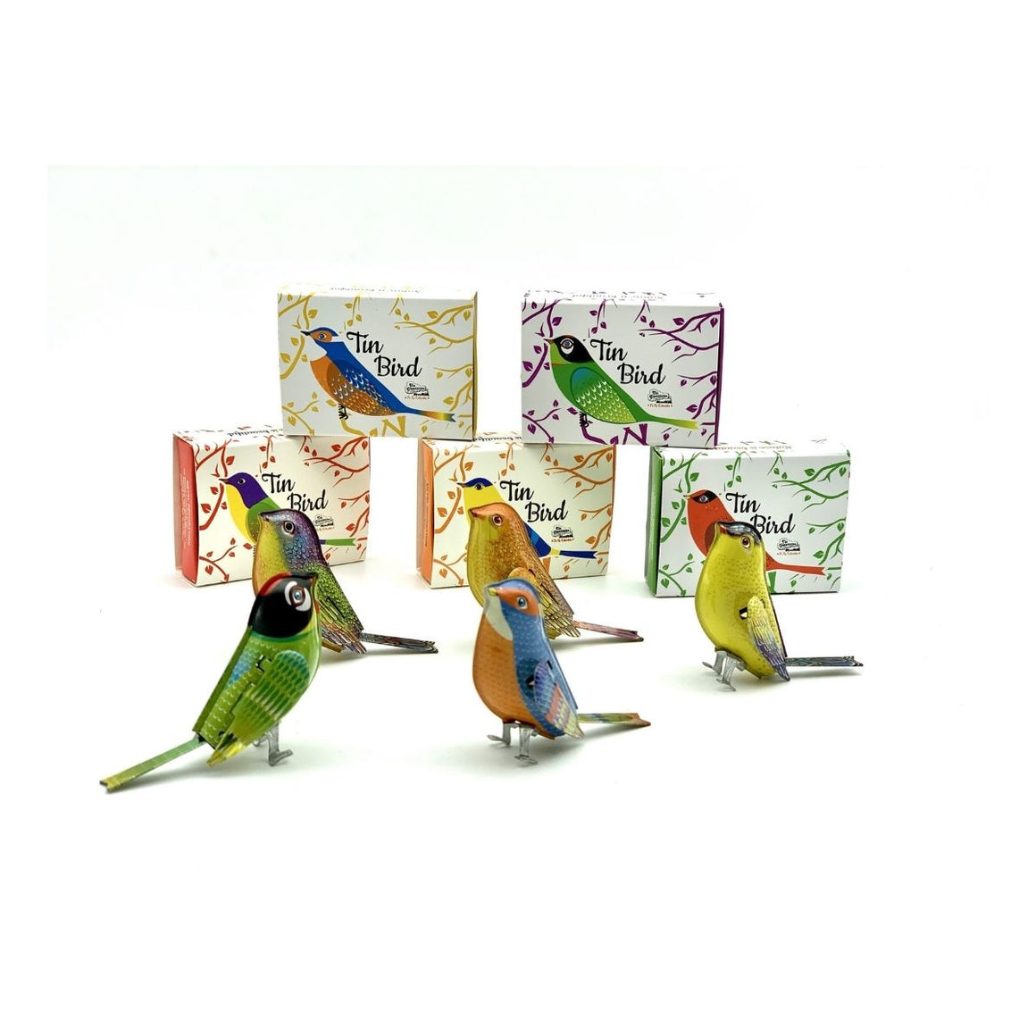 Photograph including five colourful tin birds in the front of the image with their cardboard packaging siting behind them
