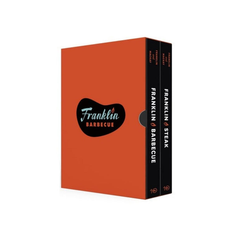Image featuring a book cover in the center which is bright red with a black shape in the middle which says Franklin Barbecue and on the right hand side the spines of the book are facing out, both of them hold different titles such as Franklin Steak and Franklin Barbecue