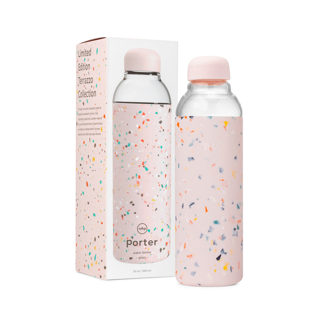 In front of a white and pink, tall packaging box is a cylindrical glass bottle with a terrazzo pink silicone sleeve and a pink curved lid. 