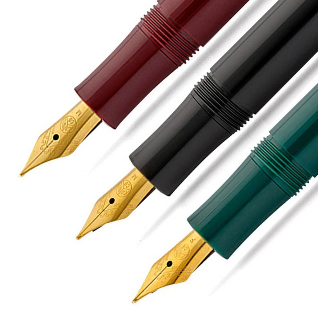 A close up of three fountain pen tips lined up showcasing the gold tip nib on a maroon, black and emerald green barrel. 