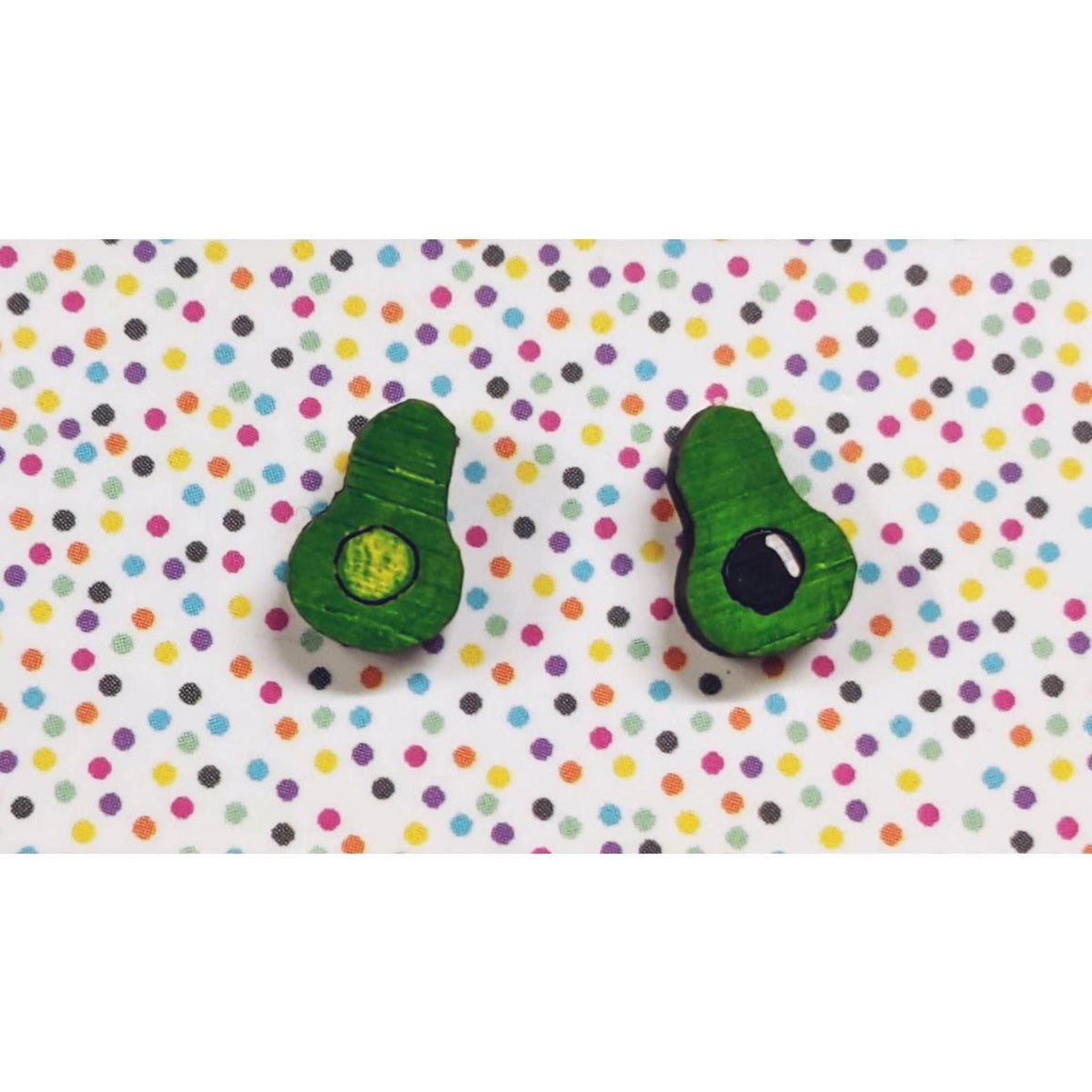 A pair of intricately hand coloured studs depicting two halves of an avocado that has been cut open. One side has the avocado stone present.