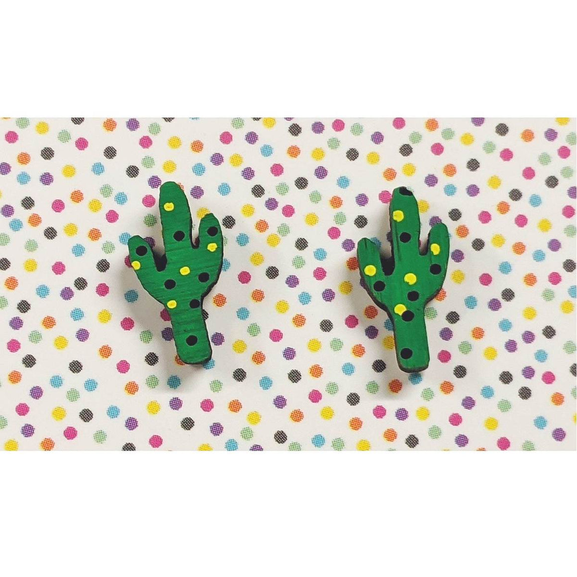 A pair of intricately hand coloured studs depicting green cactuses with black and yellow dots.