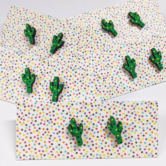 A pair of intricately hand coloured studs depicting green cactuses with black and yellow dots.