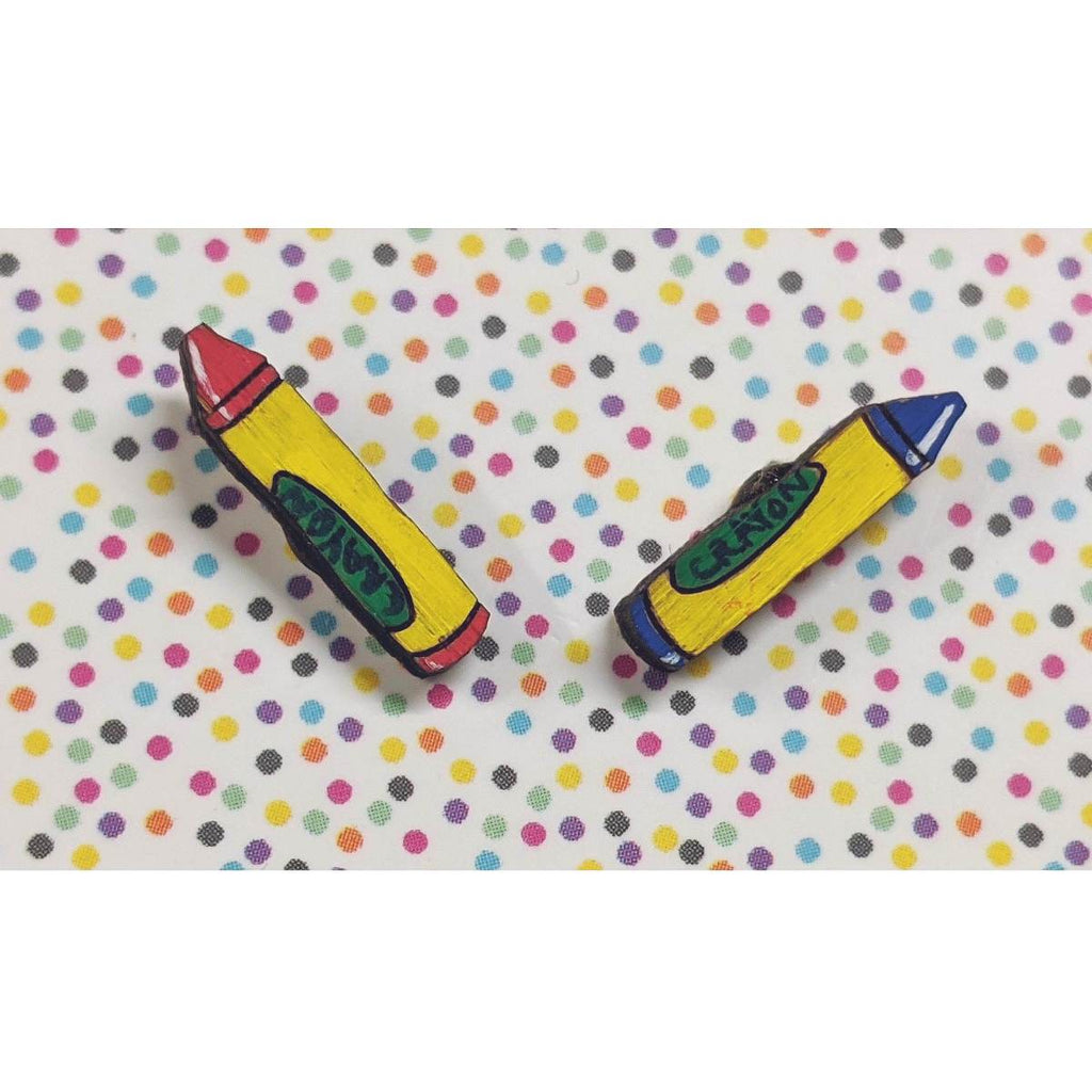 A pair of intricately hand coloured studs depicting two individual crayons. The colours crayons vary, but they all have a a yellow and green label with the word CRAYON written on them.